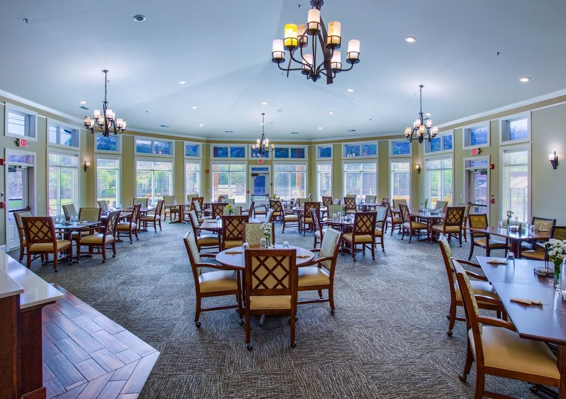 A spacious dining room with elegant chandeliers and large windows.