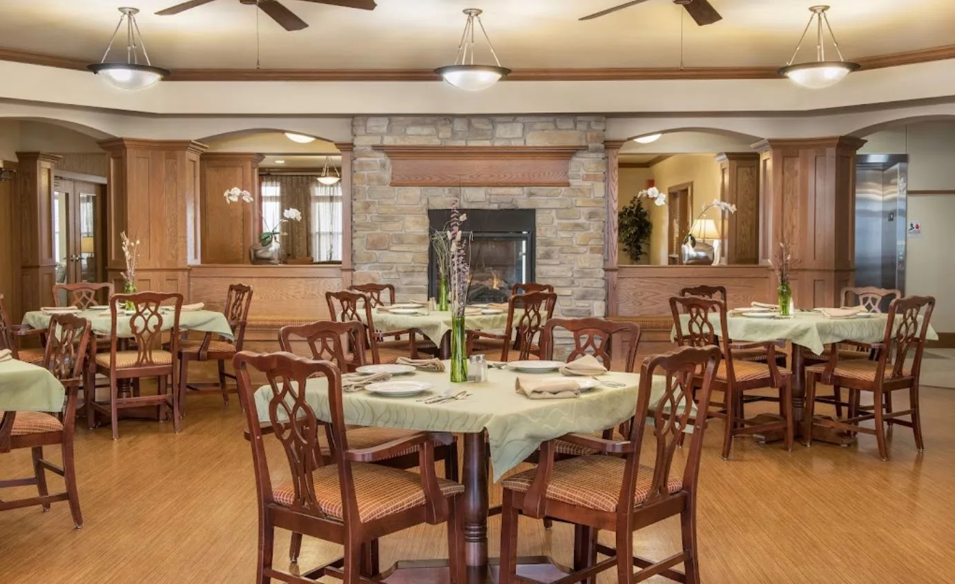 An elegant dining room with neatly set tables and a cozy fireplace.