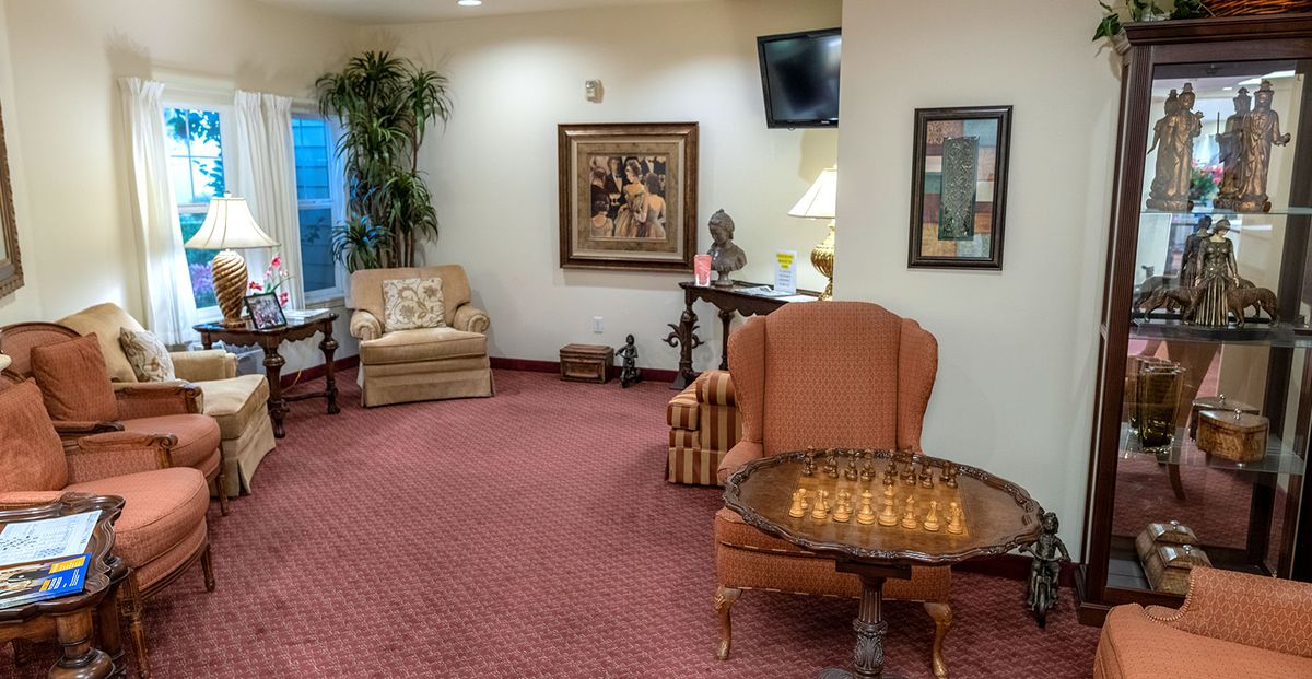 A cozy living room with plush seating, a chess board on a table, and decorative artwork.