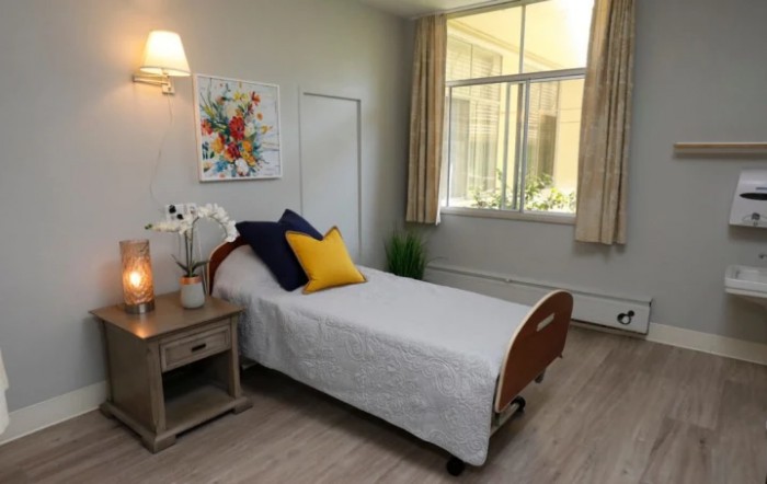 A minimalist bedroom with a single bed, nightstand, and large window.