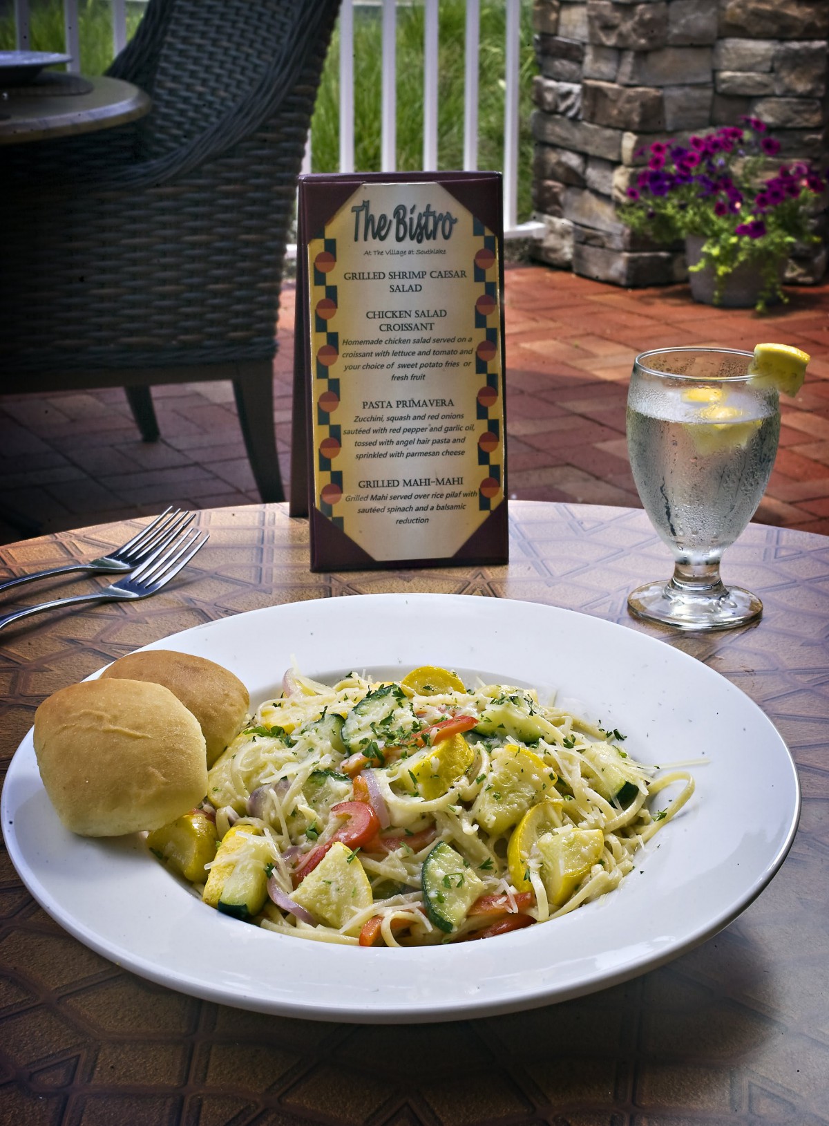 A delicious plate of pasta with bread rolls, served at an outdoor restaurant table.