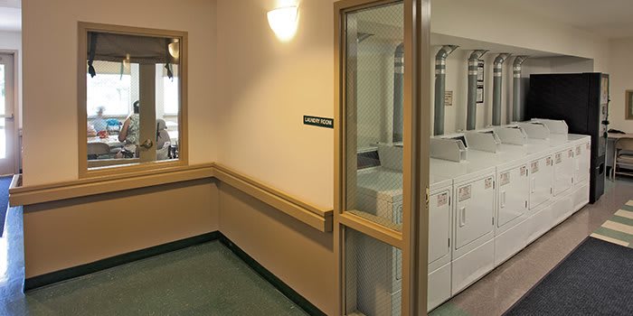 A view of a laundry room with washing and drying machines visible through a glass door.