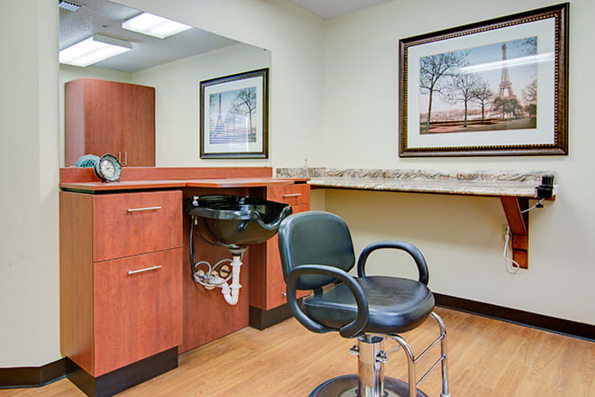 A hair salon station with a chair and sink, featuring framed artwork on the walls.