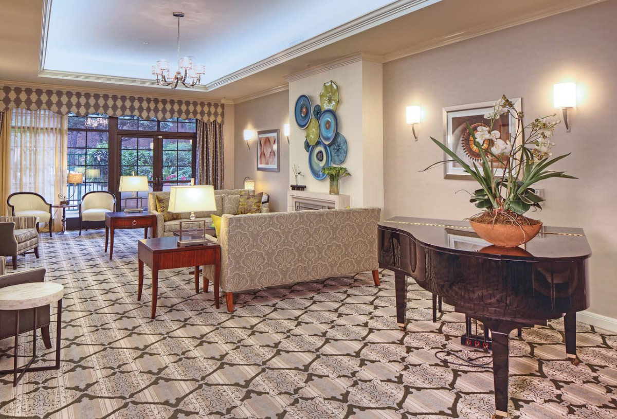 A cozy and elegant living room featuring a grand piano, stylish furniture, and decorative artwork.
