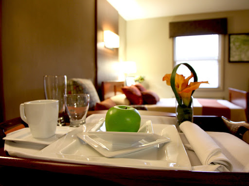 A beautifully arranged room service breakfast featuring a green apple and fresh flowers in a hotel setting.