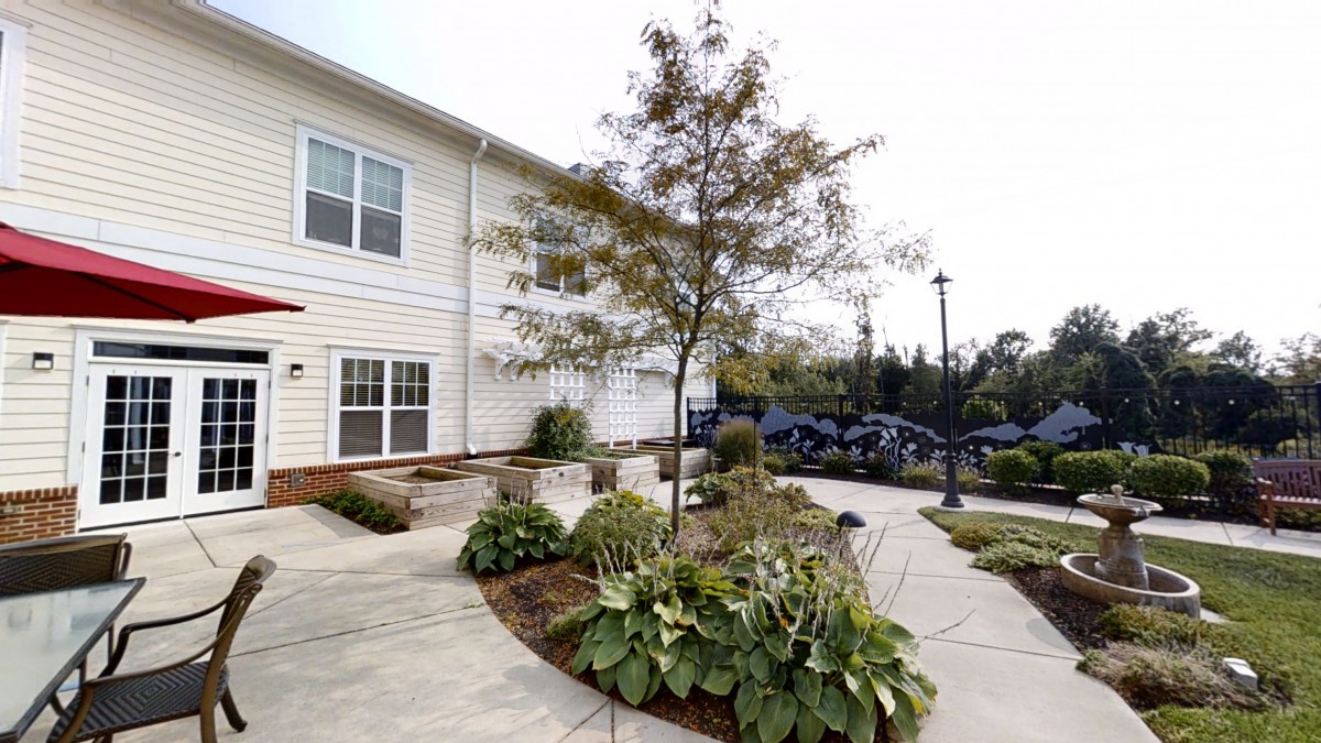A well-landscaped apartment building exterior with a tree and plants lining the pathway.