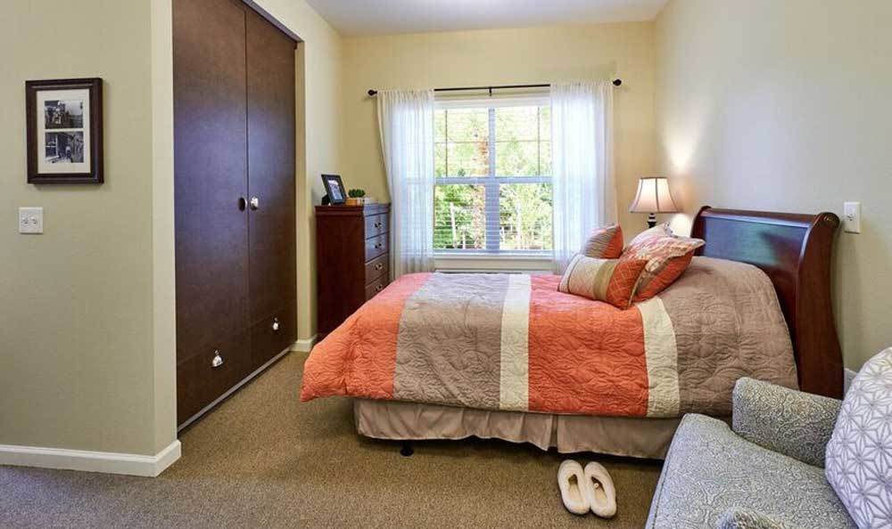 A cozy bedroom with a neatly made bed, a lamp on the bedside, and a closet.