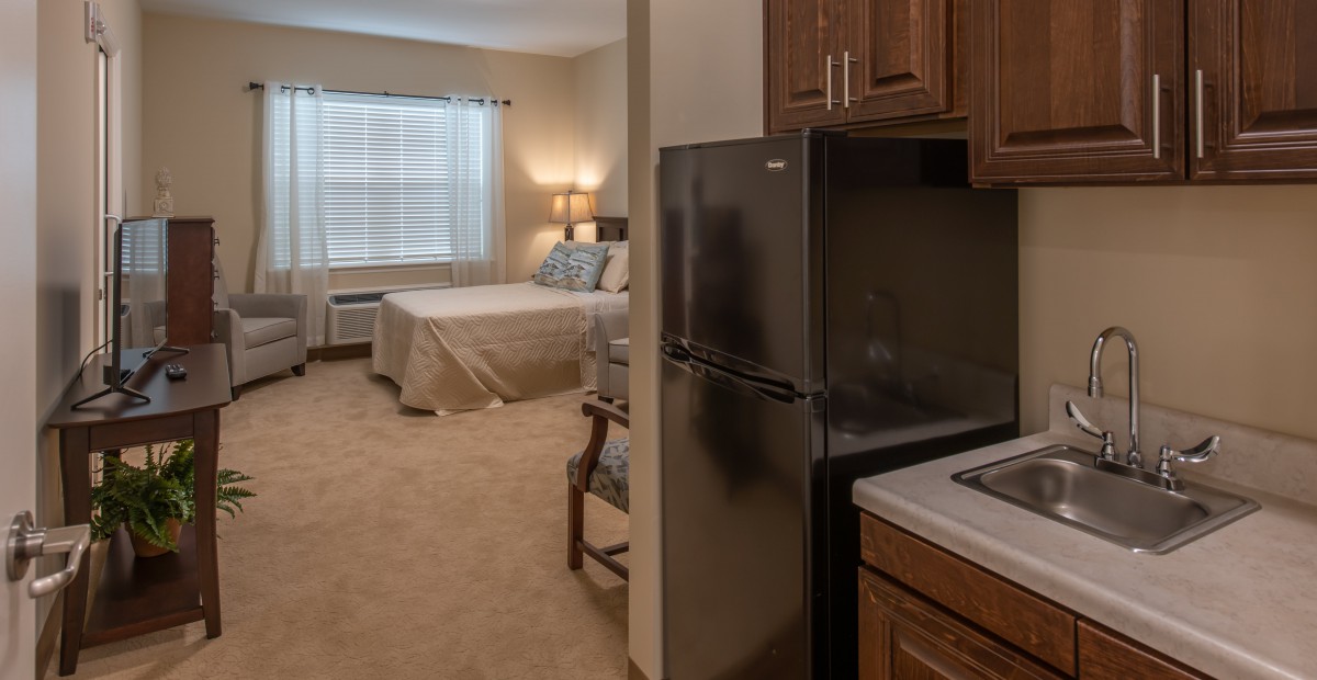A cozy studio apartment with a kitchenette and a comfortable bedroom area.