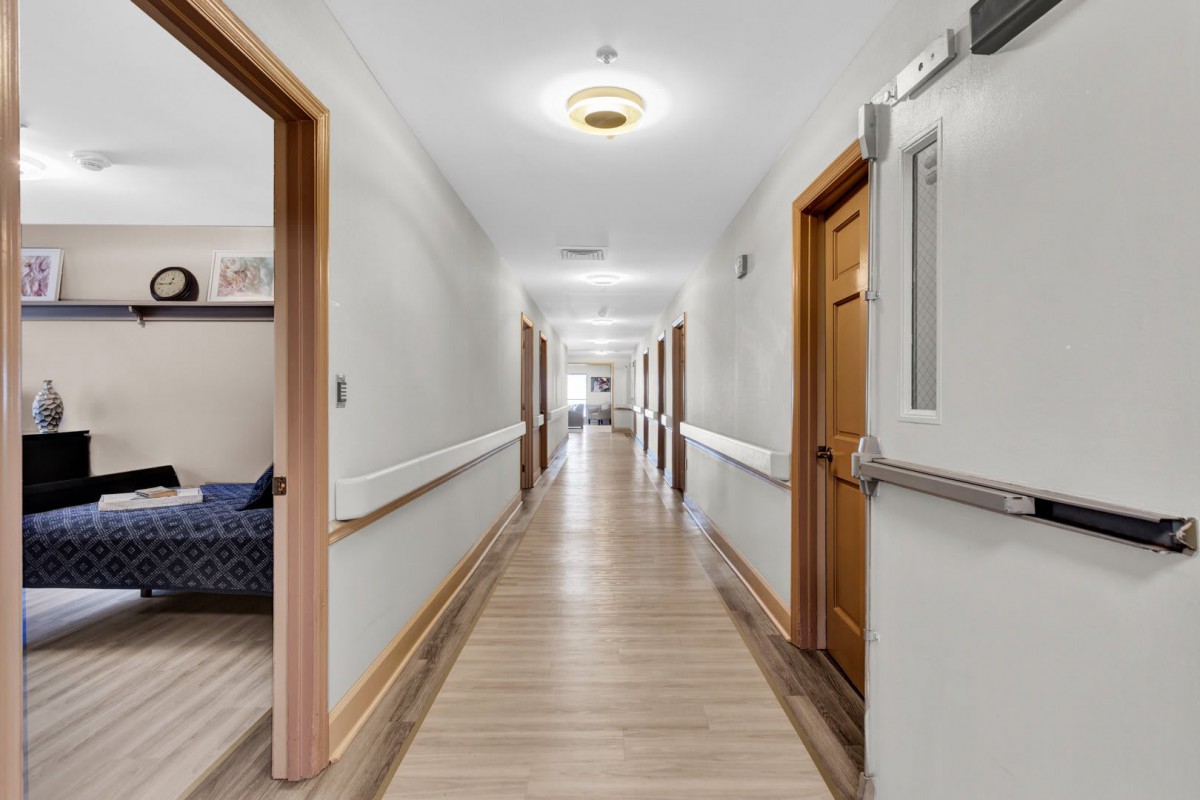 A long hallway with wooden doors and bright lighting.