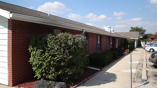 A well-maintained brick building with lush greenery in front under a blue sky.