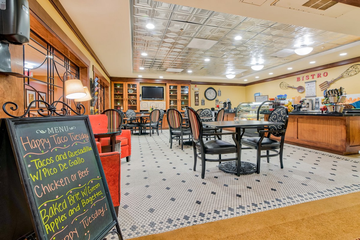 A cozy cafe interior with neatly arranged tables and chairs, featuring a prominent menu board.