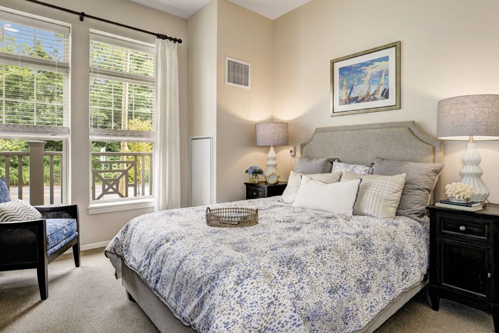 A cozy bedroom with elegant bedding, decorative artwork, and a large window.