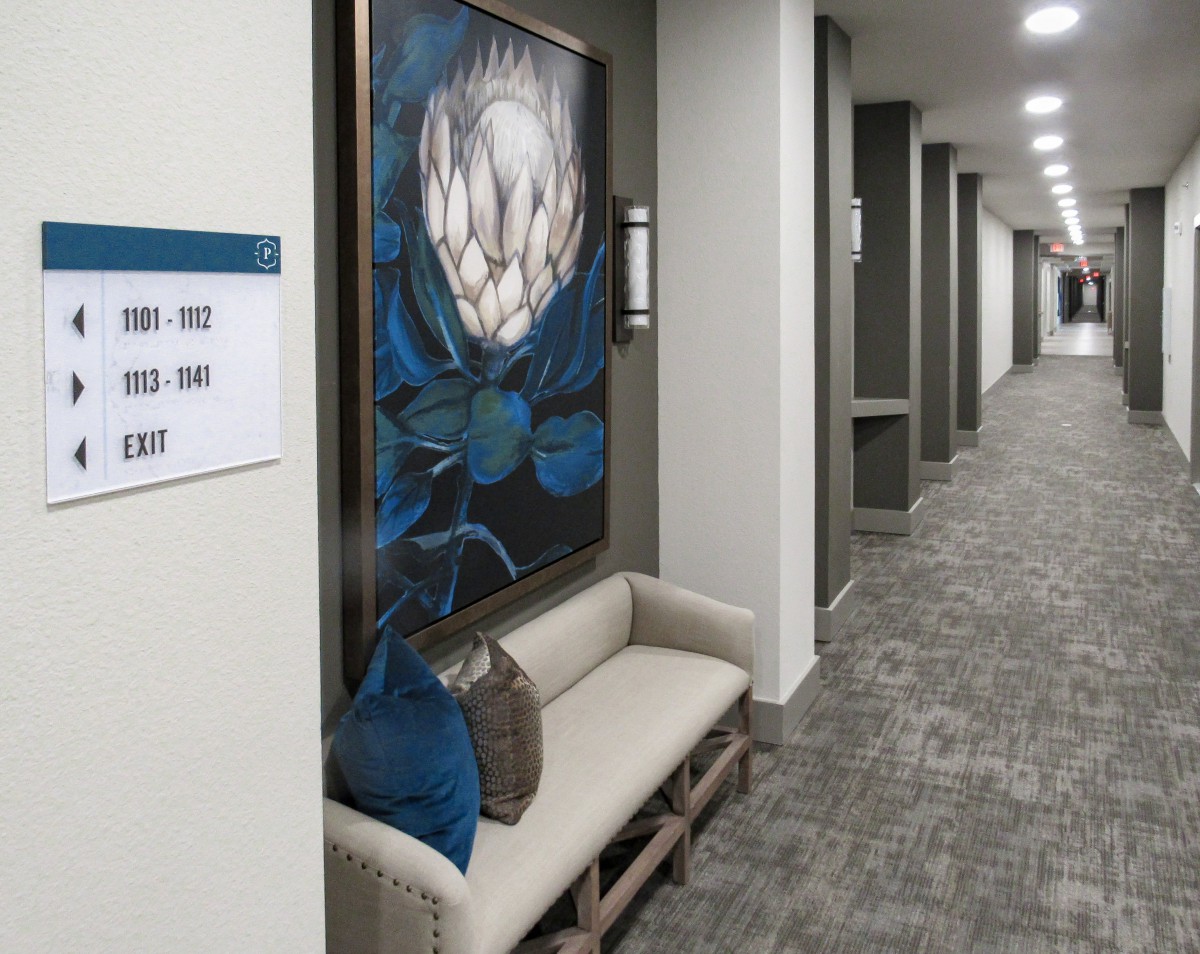A modern hallway with artwork and a seating area.