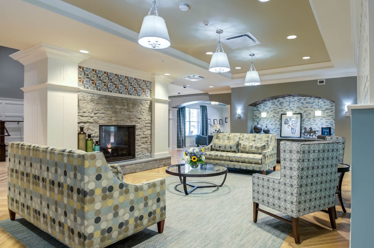 A modern living room with comfortable seating and a fireplace, elegantly lit by hanging lights.