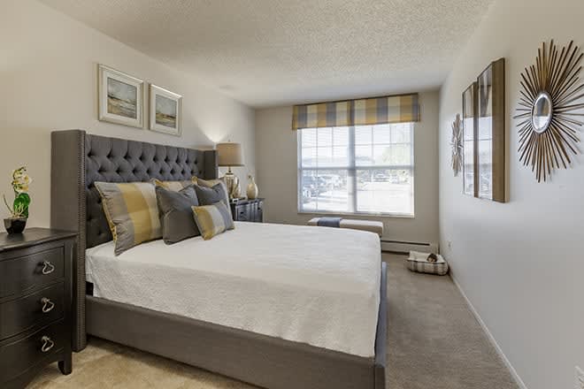A modern bedroom with a neatly made bed, pillows, and tasteful decor.