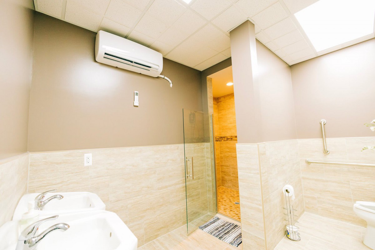 A modern bathroom featuring a shower, sink, and an air conditioning unit.
