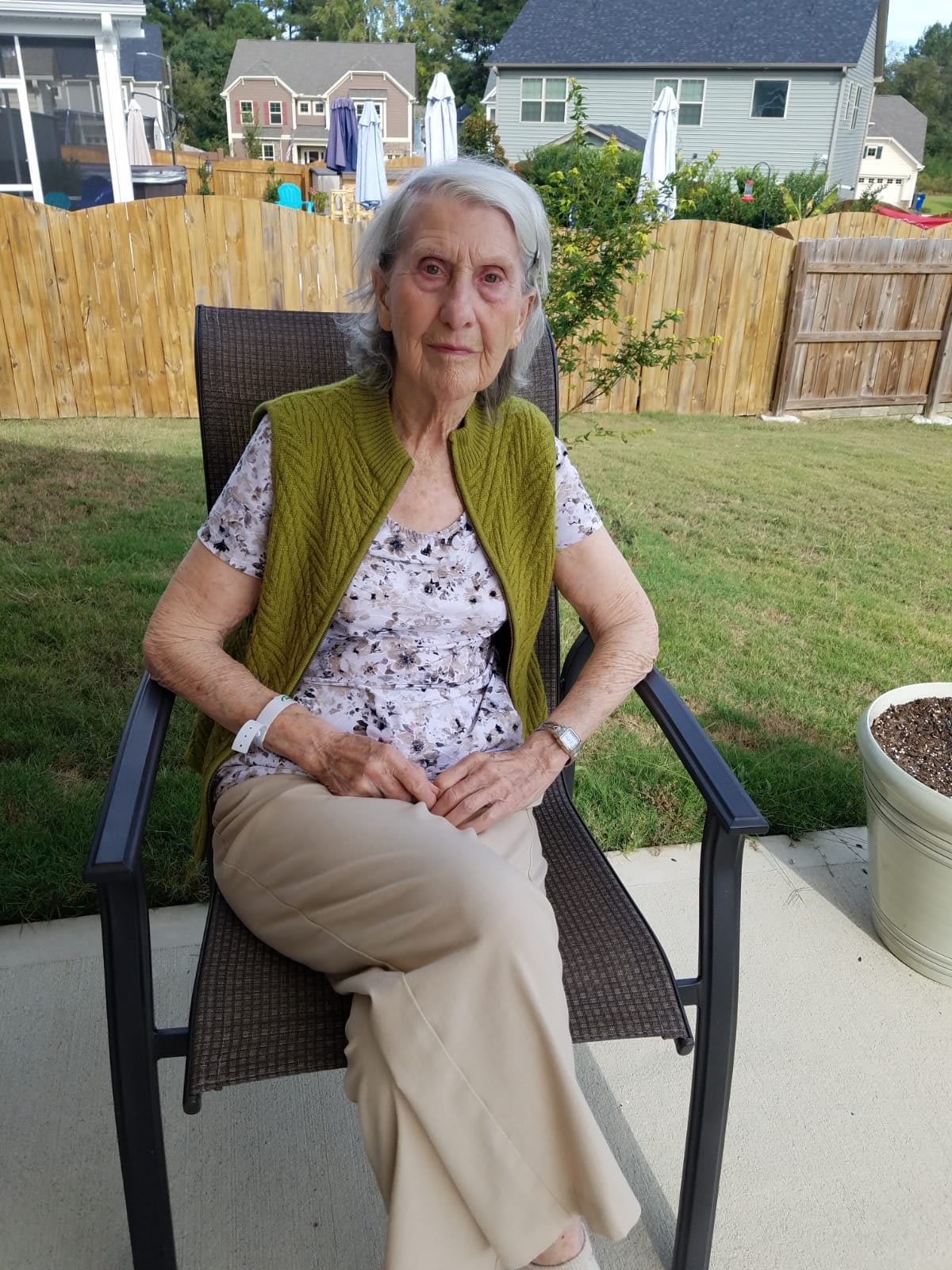A woman sitting outside in a garden, relaxing on a chair.