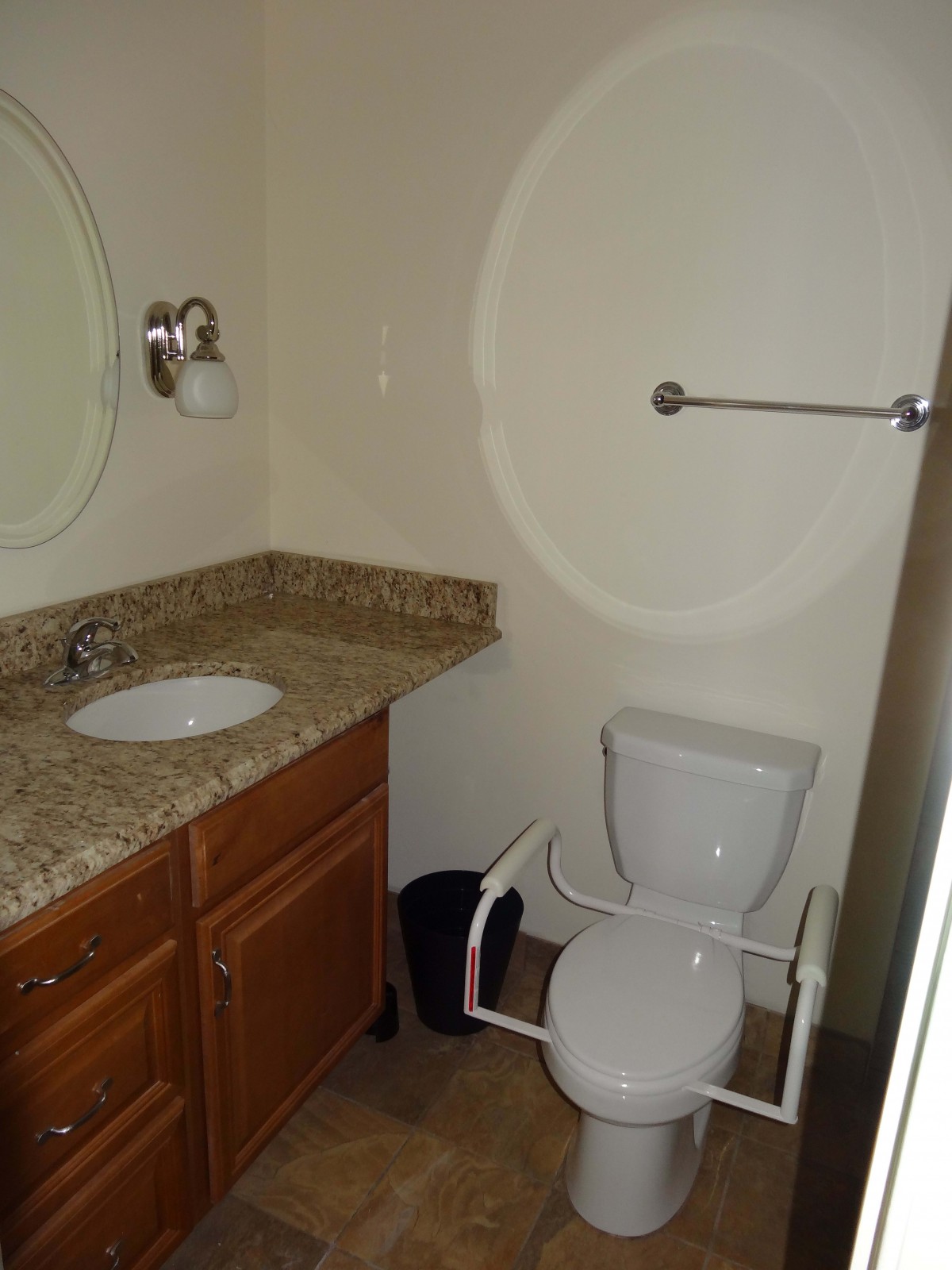 A compact bathroom with a sink, toilet, and wall-mounted mirror.