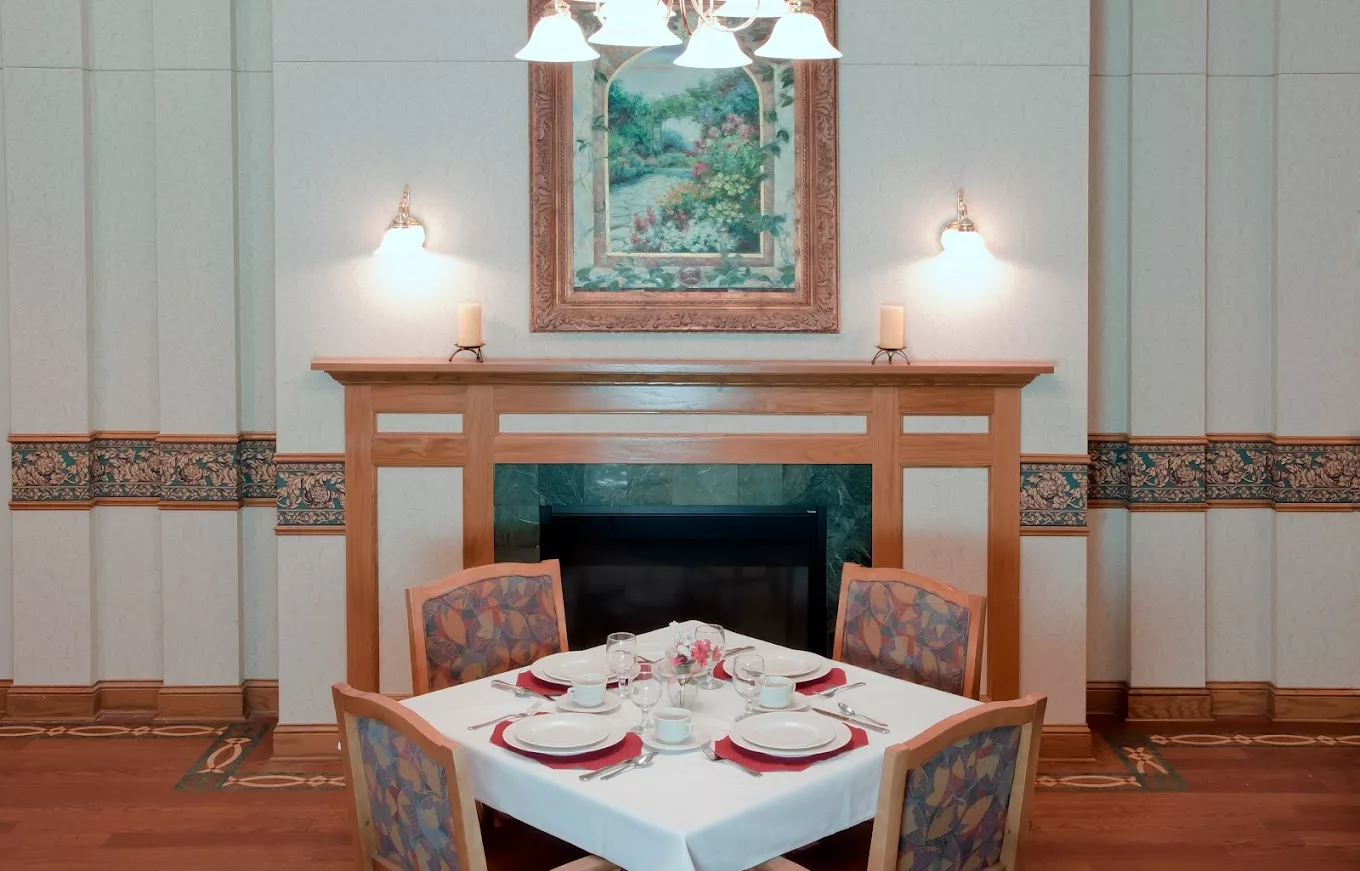 An elegantly set table in a cozy dining room featuring a fireplace, artwork, and ambient lighting.