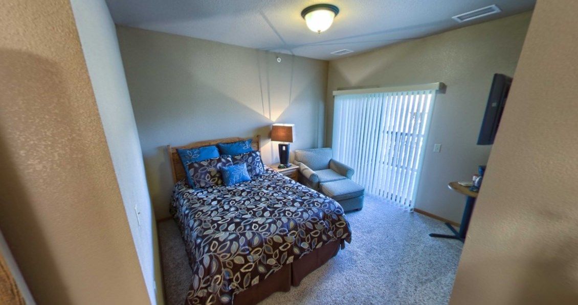 A cozy bedroom with a bed, armchair, and sliding doors.