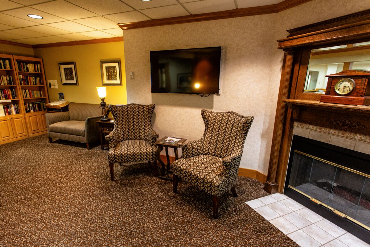 A cozy living room with chairs, a television, and a fireplace.