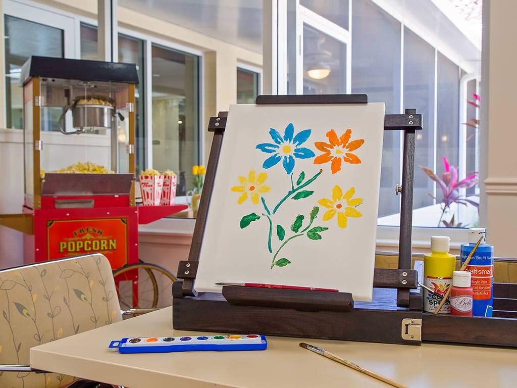 A colorful flower painting on an easel, with art supplies nearby.