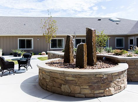 A stone fountain in a tranquil garden setting with patio seating.