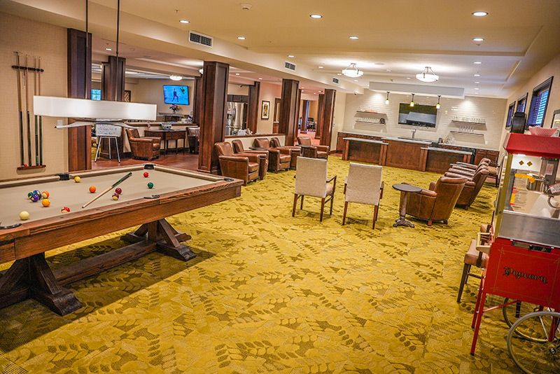 A spacious recreation room featuring a shuffleboard table, seating area, and television.