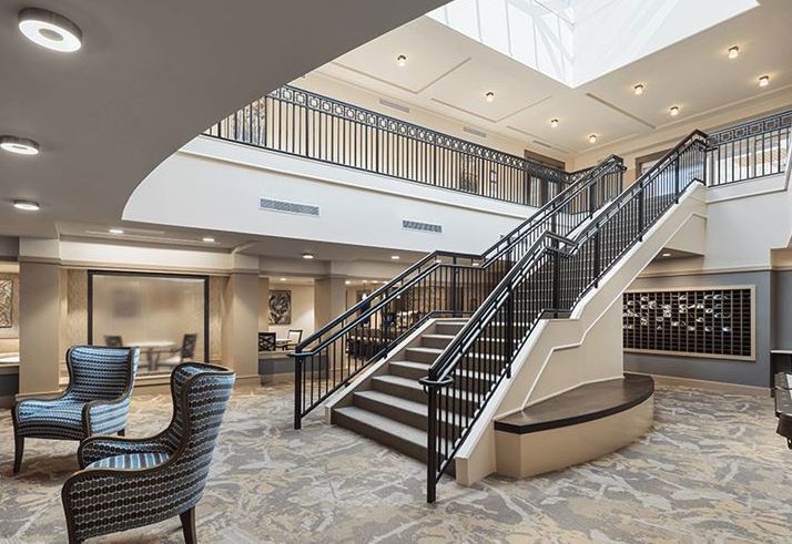 A modern lobby interior featuring a central staircase and elegant seating area.