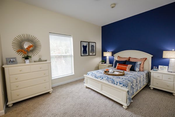 A stylish bedroom with a blue accent wall, featuring a bed, dresser, and modern decor.