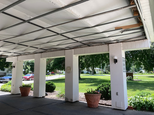 A view of a carport featuring potted plants and a lush green landscape.