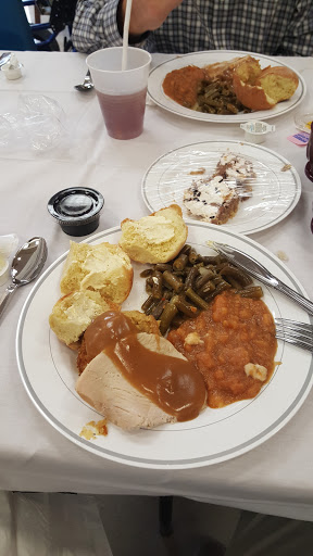 A hearty meal featuring turkey with gravy, green beans, a bread roll, and a sweet dessert.