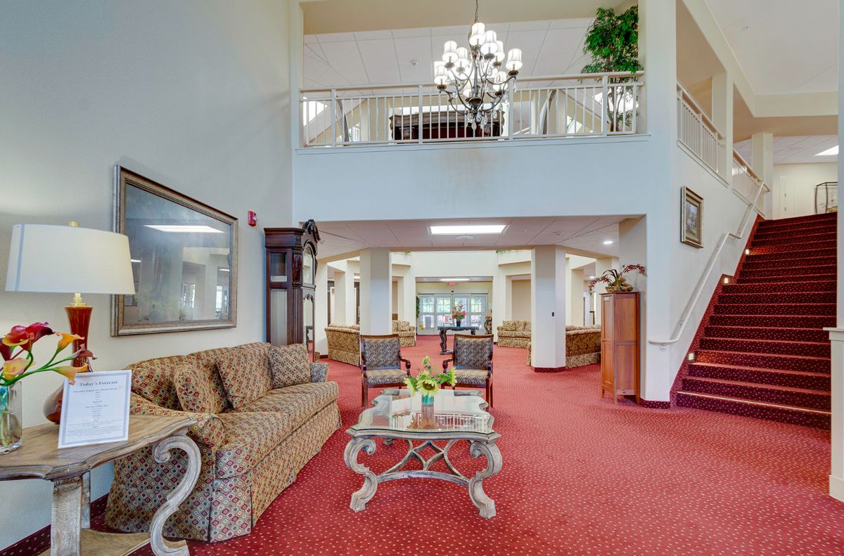 A spacious and elegant lobby area featuring comfortable seating, a chandelier, and red carpeting.