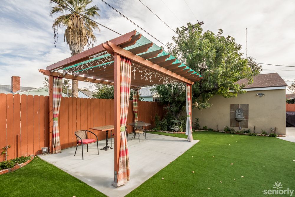 A cozy backyard featuring a pergola with outdoor seating and a well-maintained lawn.
