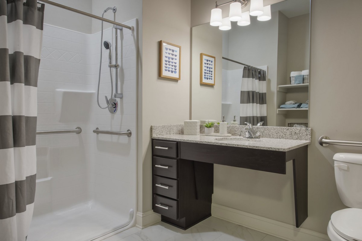 A modern bathroom with a sleek shower area, large mirror, and well-lit vanity.