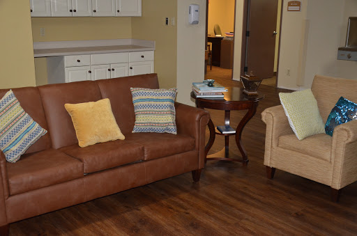 A cozy living room setup featuring a brown sofa, an armchair, and a coffee table on wooden flooring.