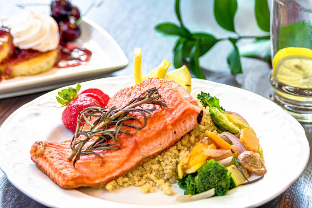 A beautifully plated dish of grilled salmon served with vegetables and quinoa.