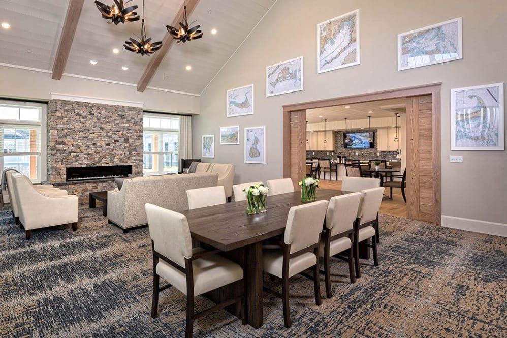 A modern and cozy living room with an open dining area, featuring a stone fireplace and elegant chandeliers.