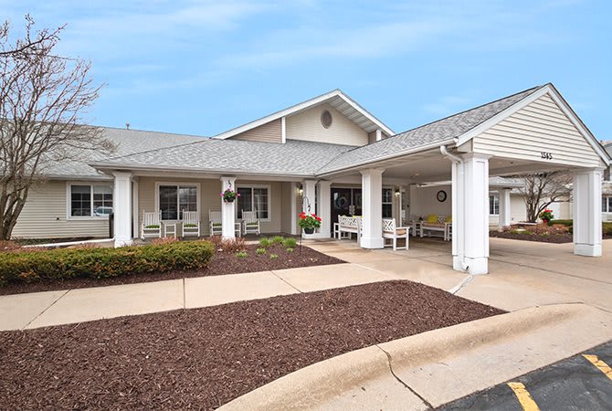 A residential-style building with a covered entrance and a landscaped front yard.