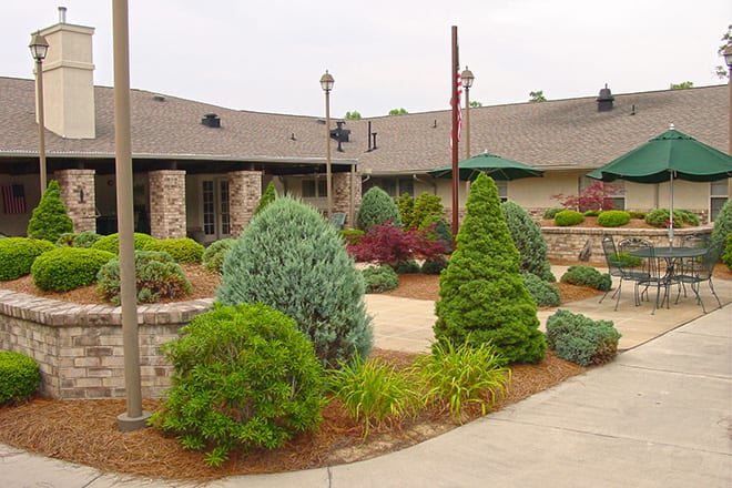 A well-maintained garden with various shrubs and plants in front of a building.