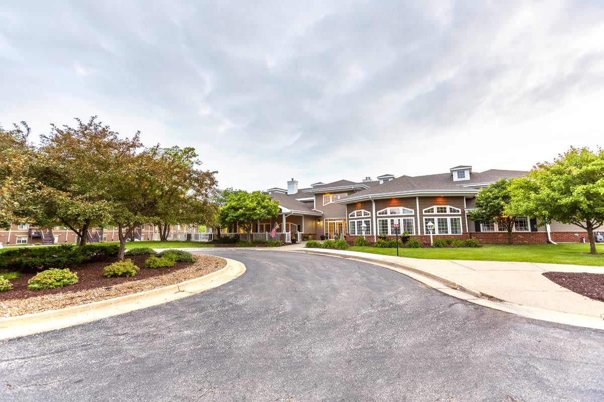 A large building with a circular driveway and landscaped surroundings under a cloudy sky.
