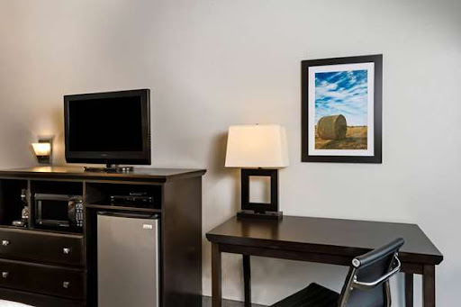 A cozy hotel room featuring a desk, lamp, and a TV.