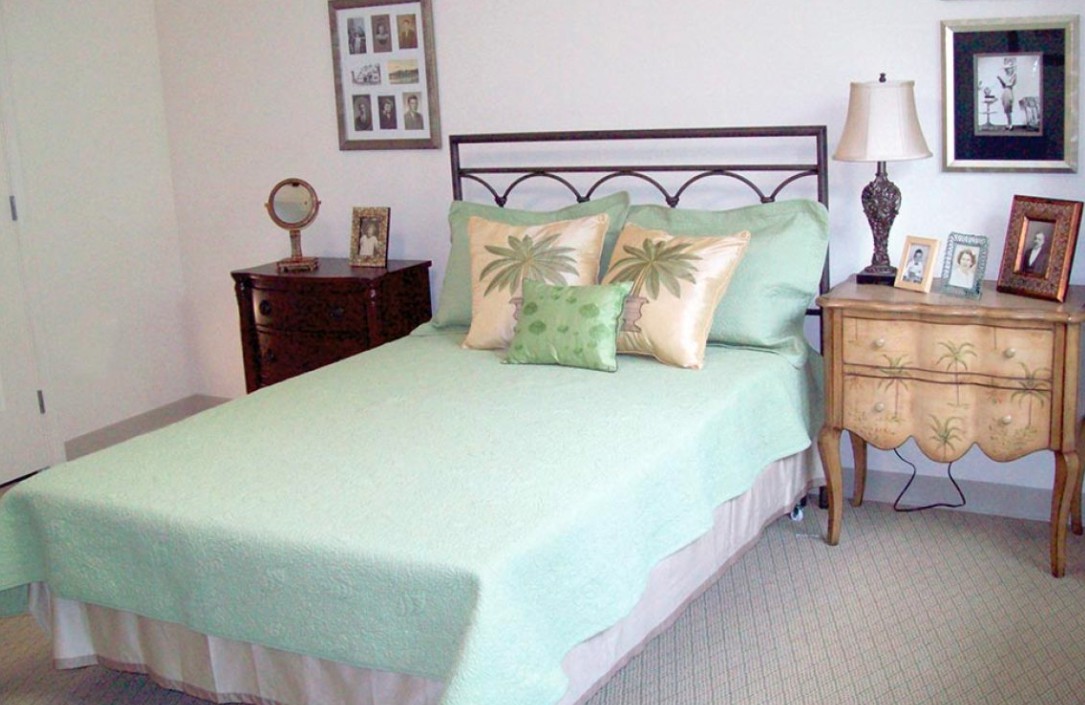 A neatly arranged bedroom with a pastel green bedspread and decorative pillows.