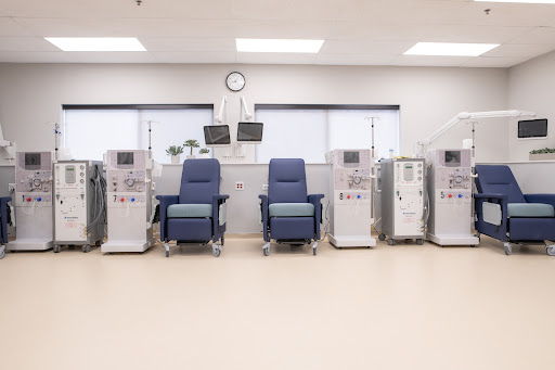 A clean and organized dialysis treatment area featuring multiple medical chairs and equipment.
