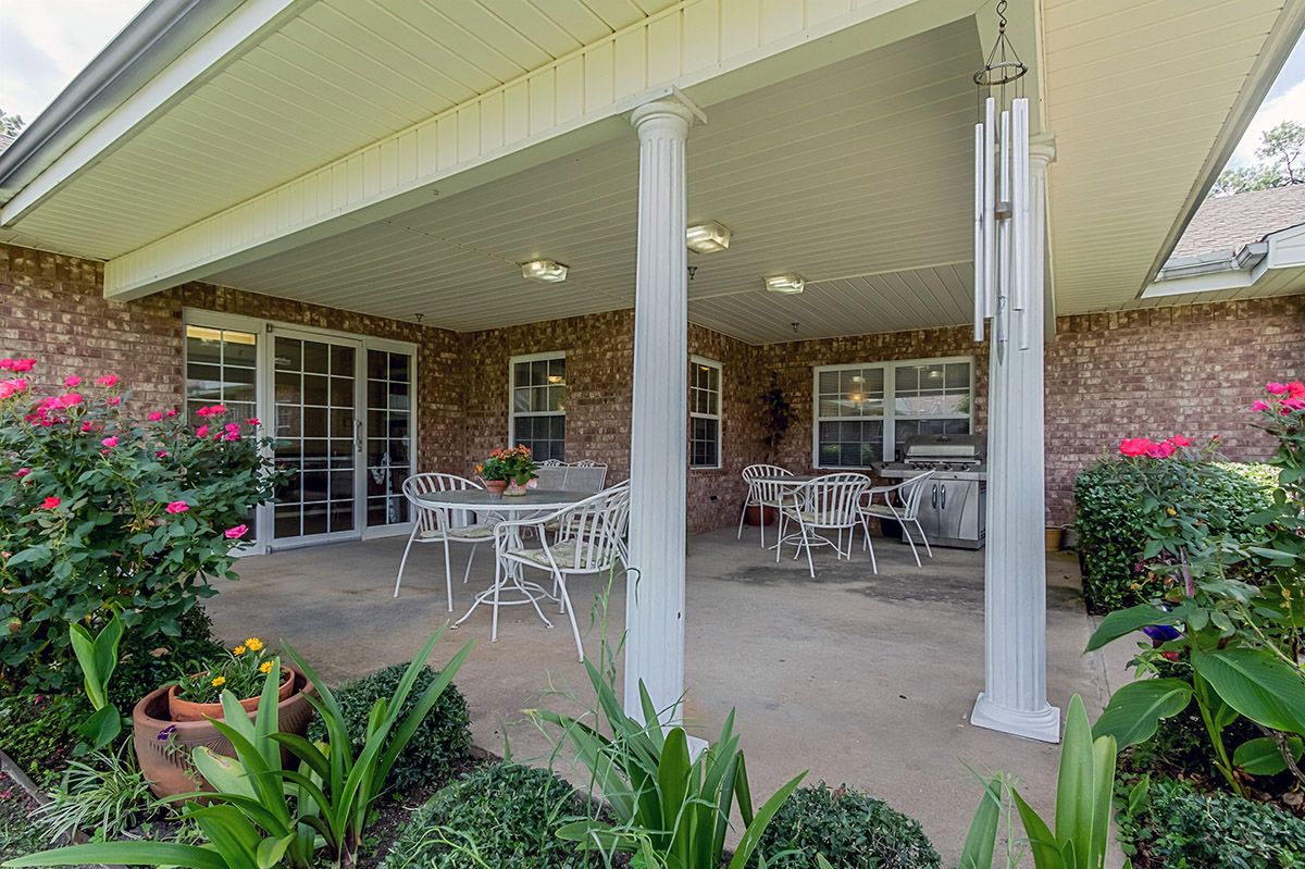 A cozy covered patio with outdoor furniture and garden views.