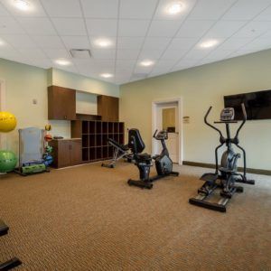 A small fitness room featuring stationary bikes, an elliptical machine, and yoga balls.