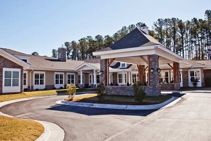 A modern building with a covered entrance and landscaped surroundings.