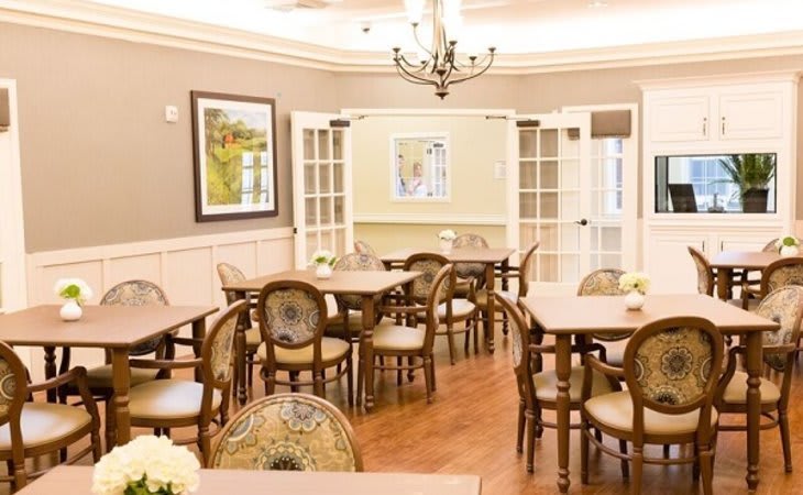 A warmly lit dining area with elegant furniture and artwork on the walls.