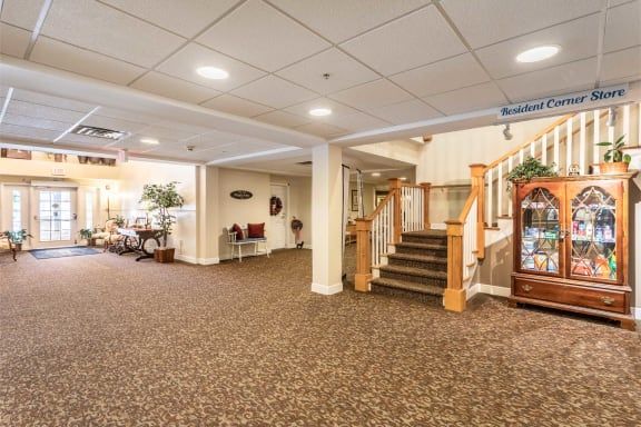 A well-lit lobby with carpeted flooring and a staircase leading upstairs.