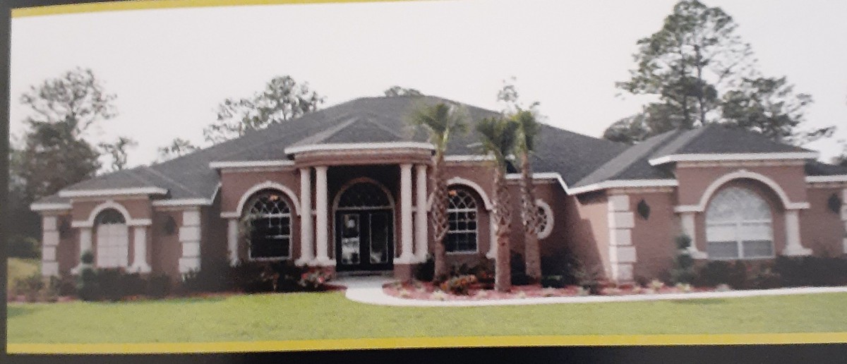 A suburban house with a manicured lawn and palm trees in the front yard.